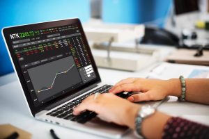 A person analyzing financial data on a laptop with stock charts and market indicators on the screen, representing real-time monitoring and strategic investing in ETFs.