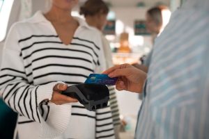 A customer makes a purchase using a credit card through a contactless terminal, illustrating the convenience of proximity payments with credit cards in a modern retail environment.