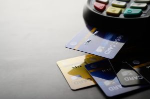 A set of colorful credit cards partially inserted into a point-of-sale terminal, representing electronic payment and modern financial transactions using credit cards.